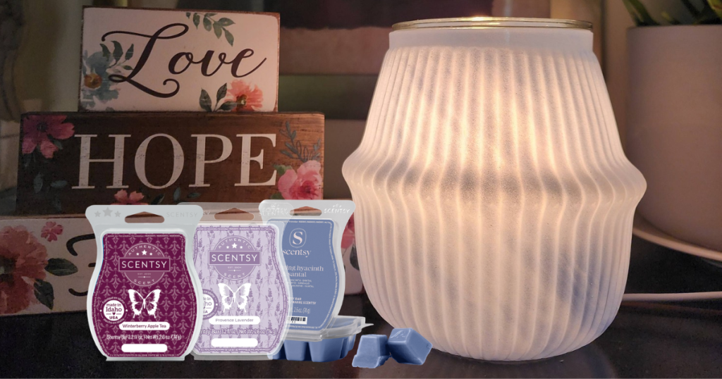 Photo with 3 bars of Scentsy Wax and a Warmer that is a light blue in color and has a light bulb to give it that is set on a table with the words love, hope on decor pieces in the background.